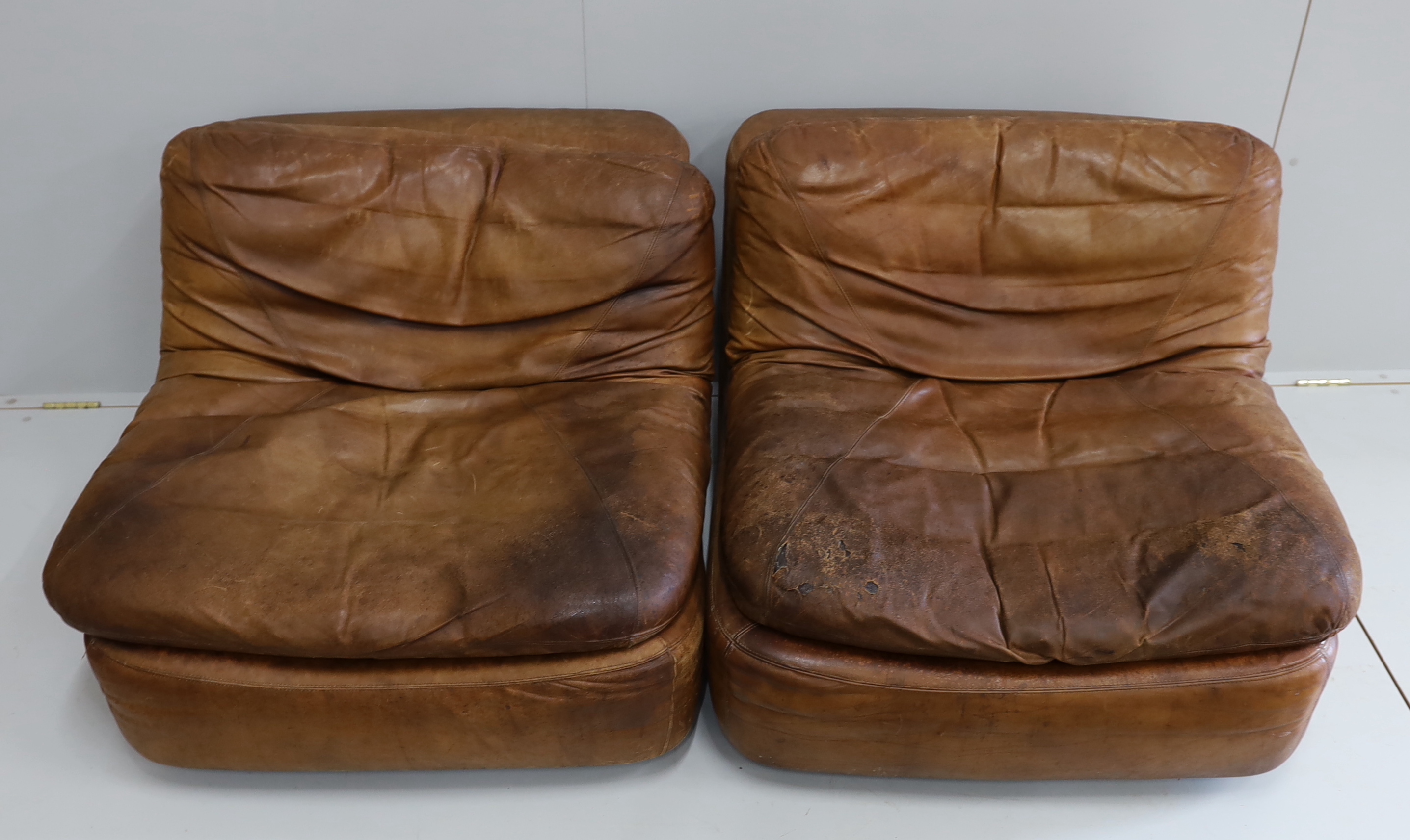 A pair of German Dreipunkt tan leather easy chairs, width 86cm, depth 96cm, height 60cm